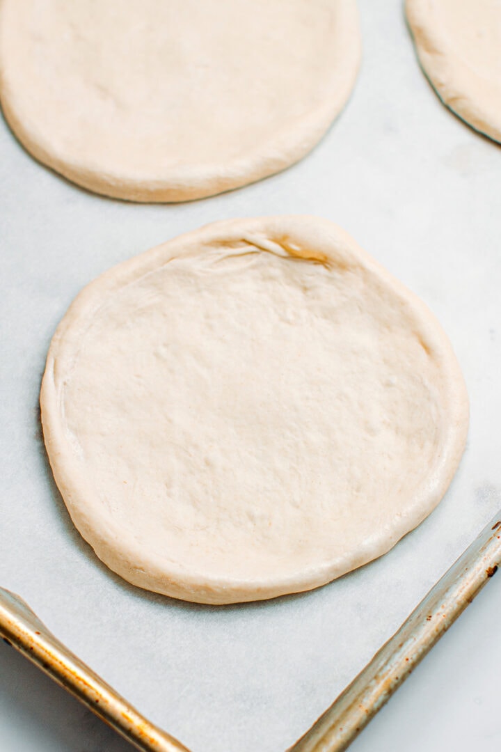 Stretched pizza dough on a baking sheet.