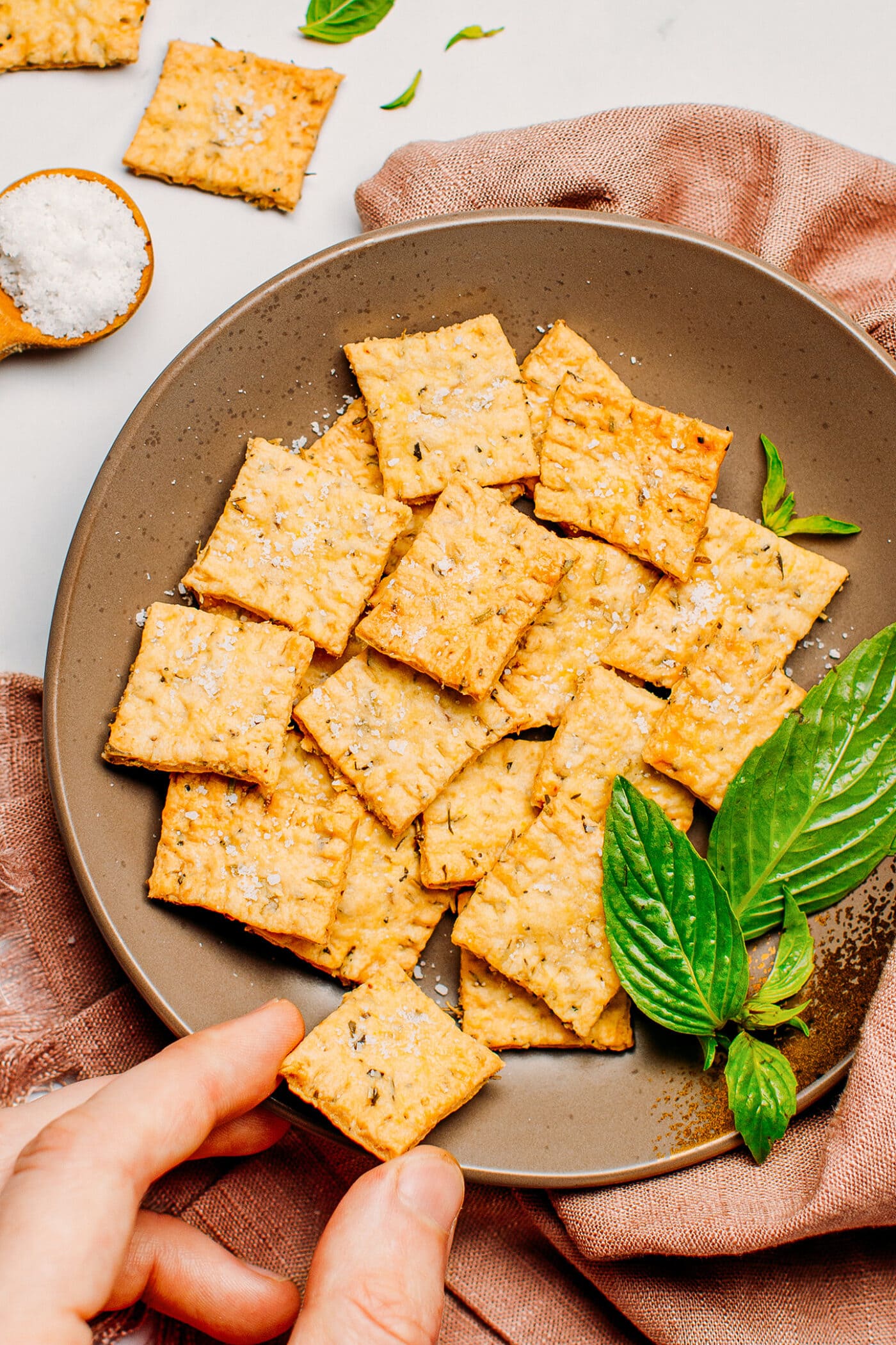 Herb crackers on a plate with sea salt and fresh basil.