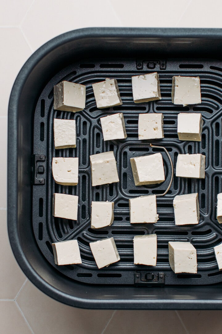 Tofu in the basket of an air fryer.