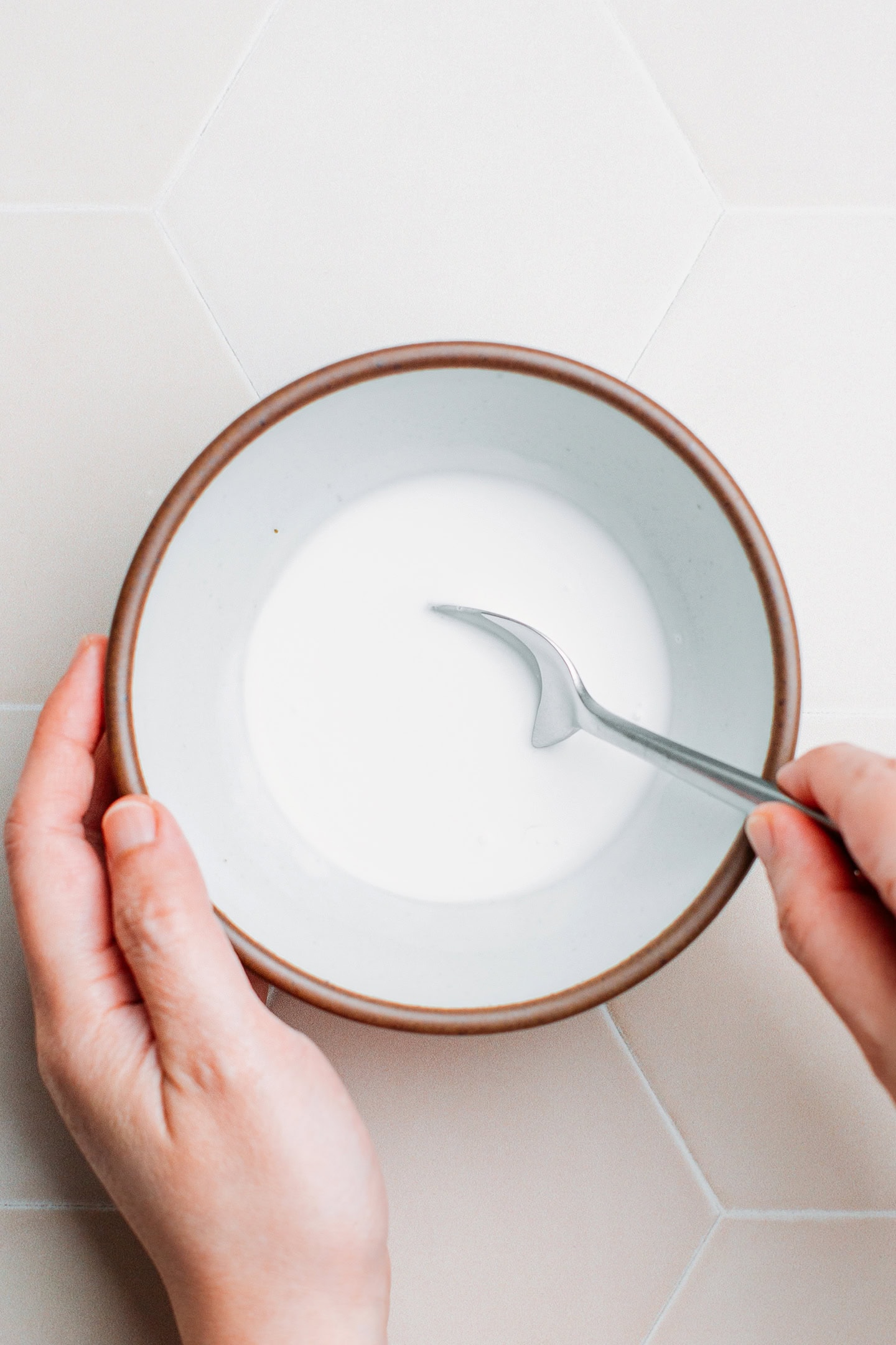 Stirring coconut milk with sugar and salt in a small bowl.