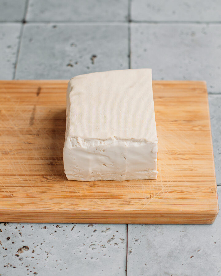 Block of tofu on a cutting board.