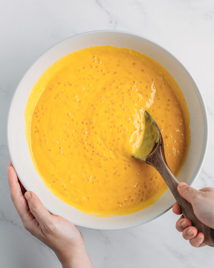 Mixing cooked tapioca pearls with puréed mango in a bowl.