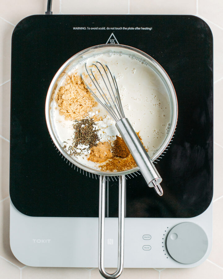 Coconut milk, nutritional yeast, dried thyme, and cumin in a saucepan.