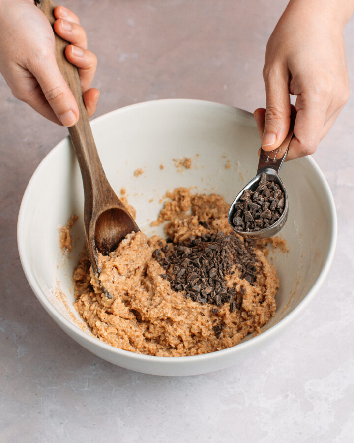 Adding chopped chocolate to a batter in a mixing bowl.