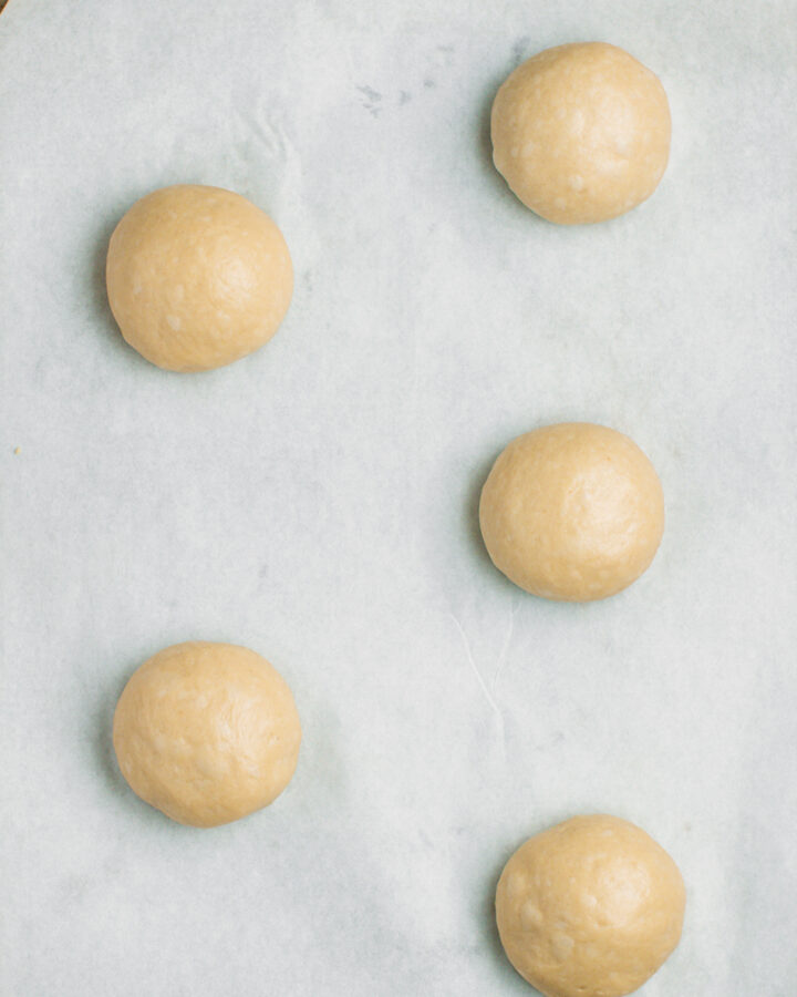 Five balls of dough on a baking sheet.
