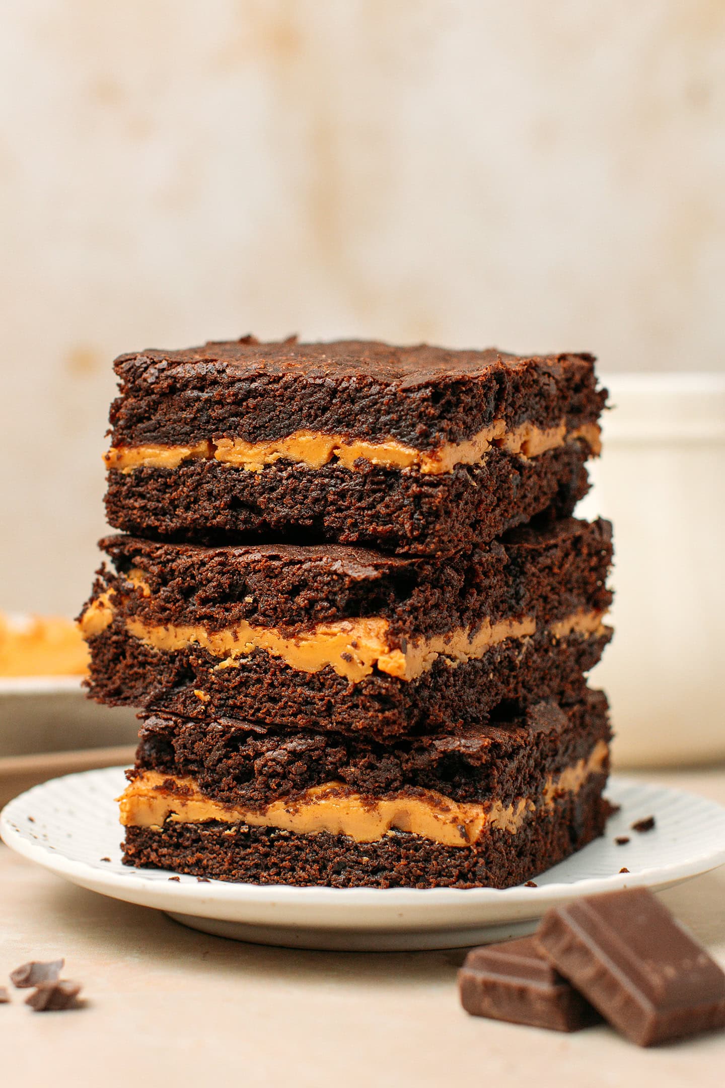 Three squares of brownies stacked on a ceramic plate.