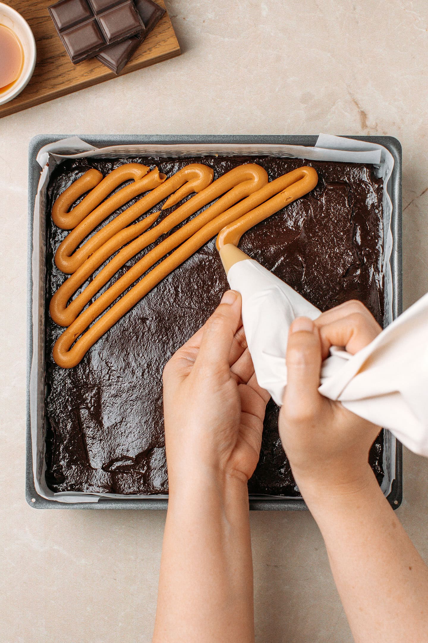 Piping peanut butter over a layer of brownie batter.