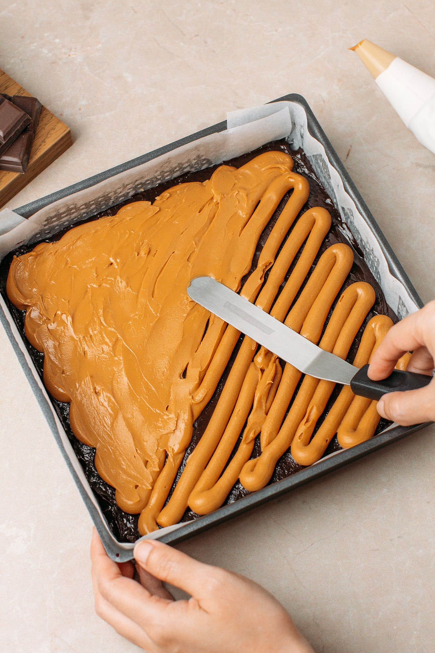 Using an icing spatula to spread peanut butter in a pan.