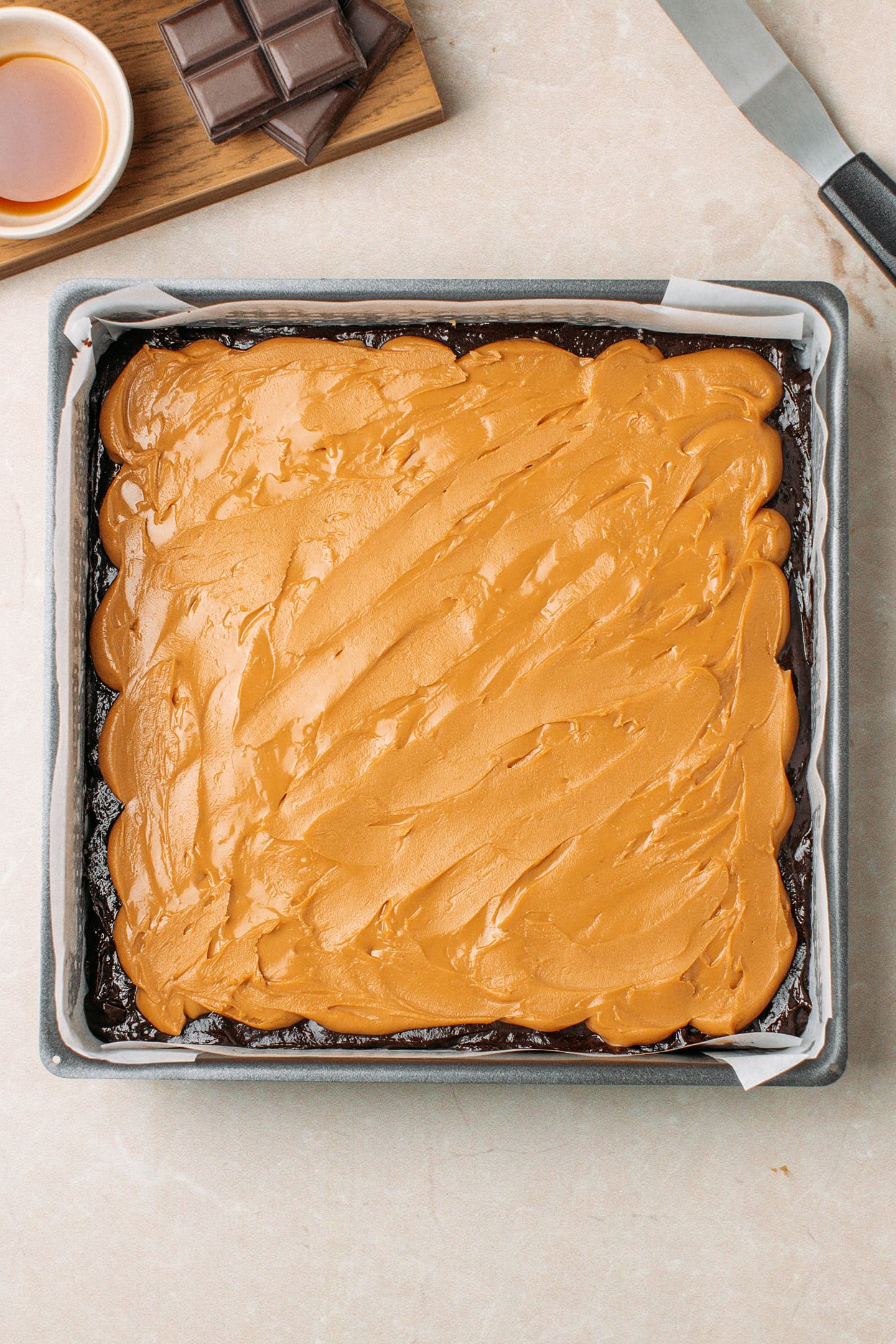 Thick layer of peanut butter over a layer of brownie batter in a pan.