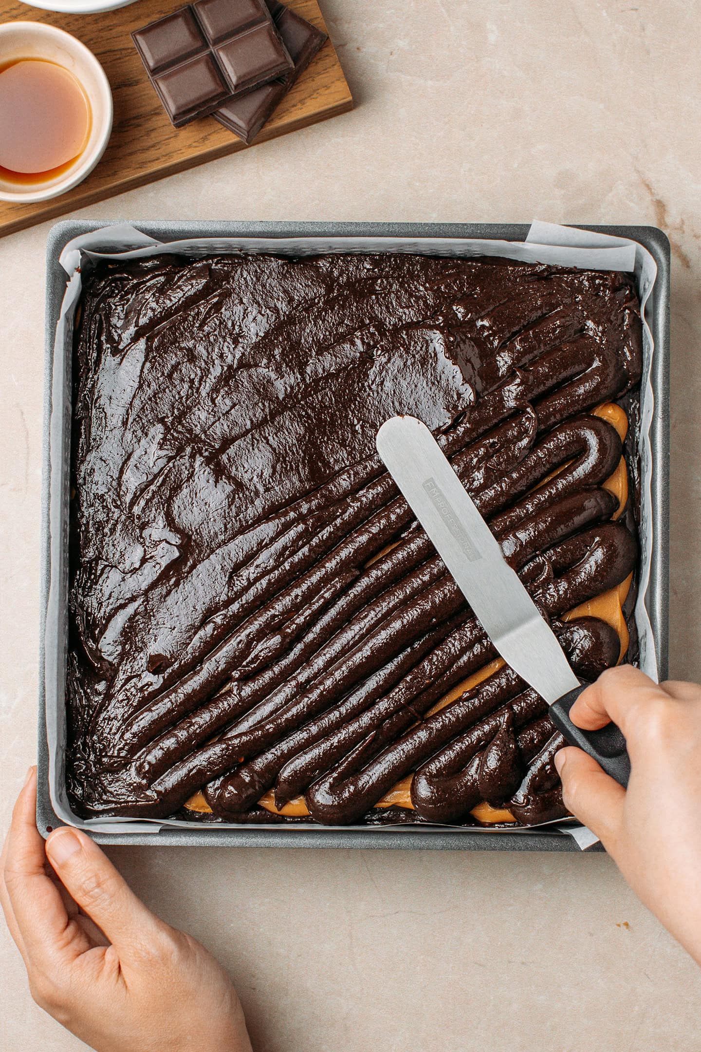 Spreading brownie batter over a layer of peanut butter.