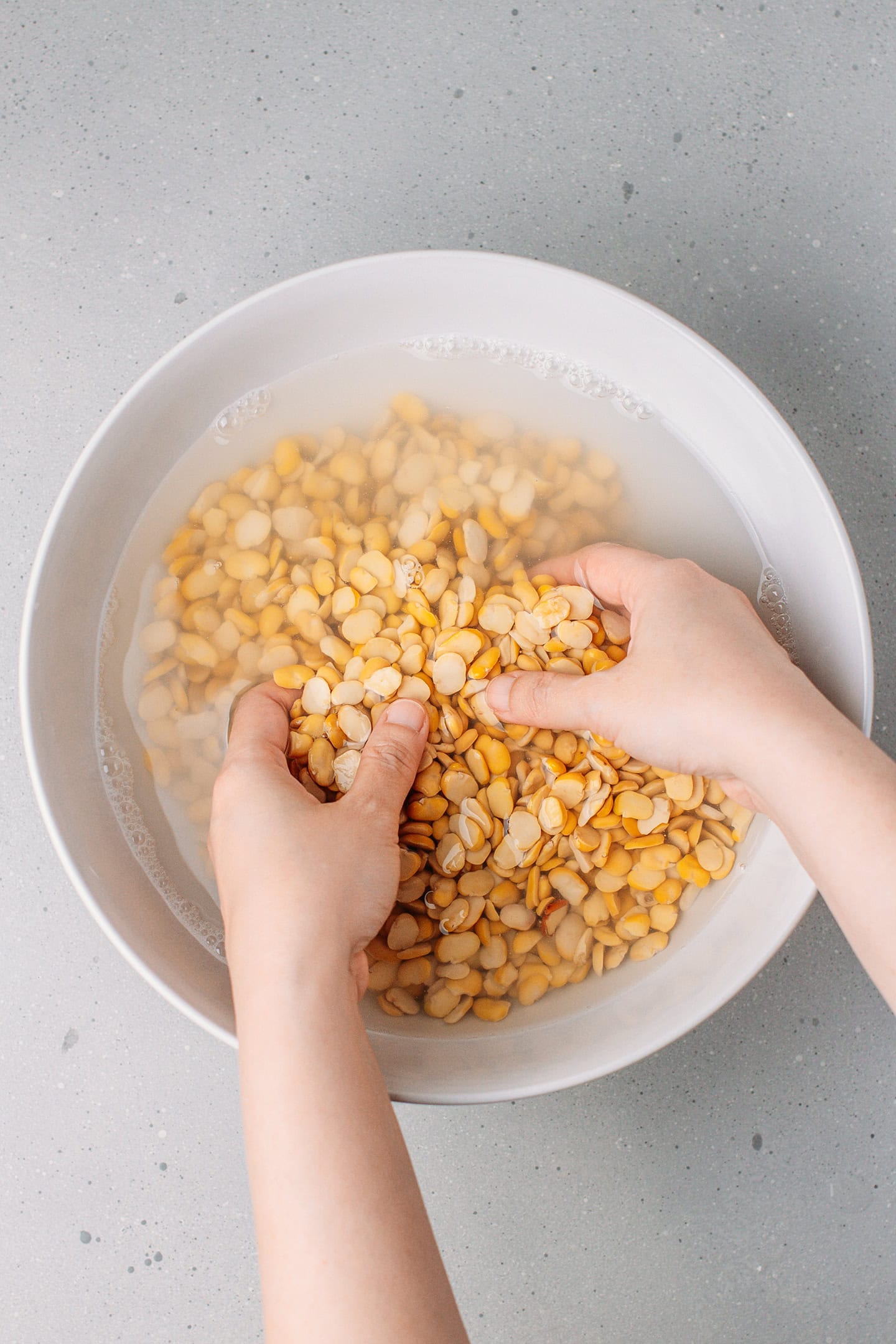 Rinsing fava beans in a bowl.