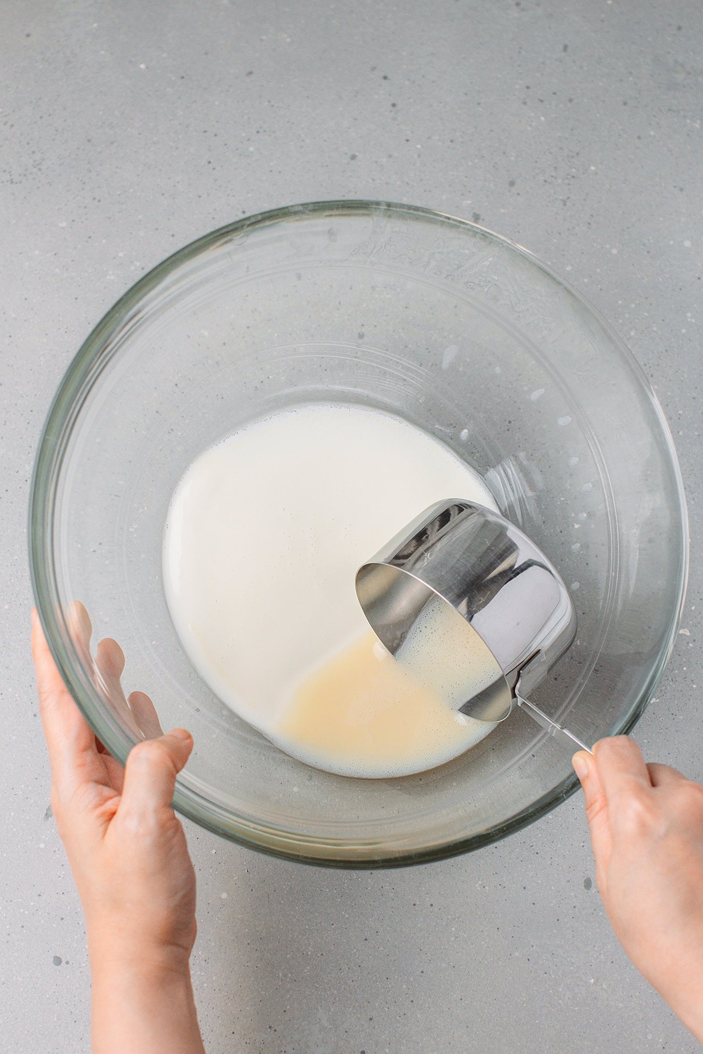 Scooping out fava bean milk from a glass bowl.